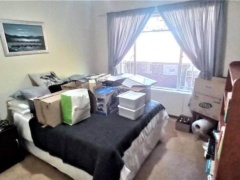 A bedroom featuring carpeted flooring and a window with curtain rails, offering a functional space ready for personalization.