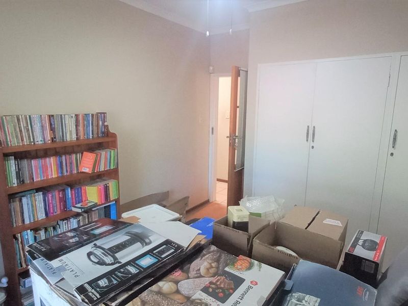 A bedroom featuring built-in cupboards and a ceiling fan, currently used for storage.