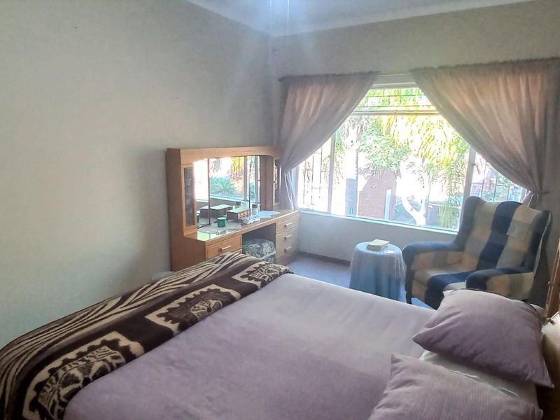 A standard bedroom featuring a large window with natural light, providing a view of the exterior garden area.