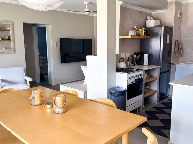 Open-plan living and dining area featuring a modern kitchen with gas stove, stone countertops, and neutral finishes, creating a cohesive and functional living space.