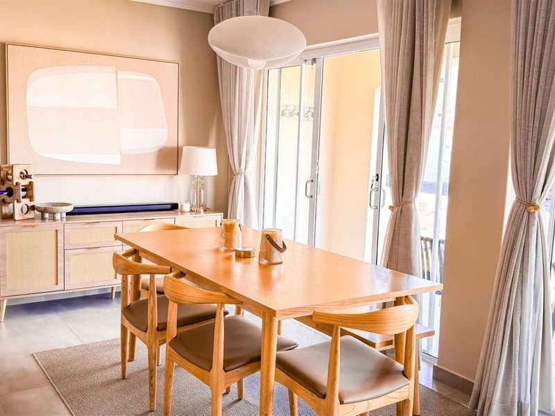 A bright and well-maintained dining area featuring tiled flooring and large sliding glass doors that provide access to an outdoor patio space.
