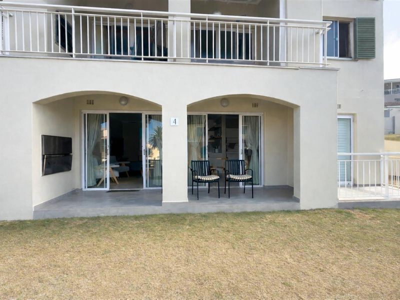 A ground-floor patio area featuring tiled flooring, sliding glass doors, and a covered archway design, providing direct access to the outdoor lawn.
