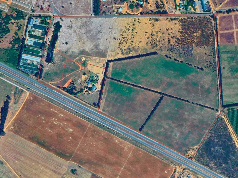 An aerial view of a large residential vacant land parcel with defined boundaries, showing open fields and access roads.