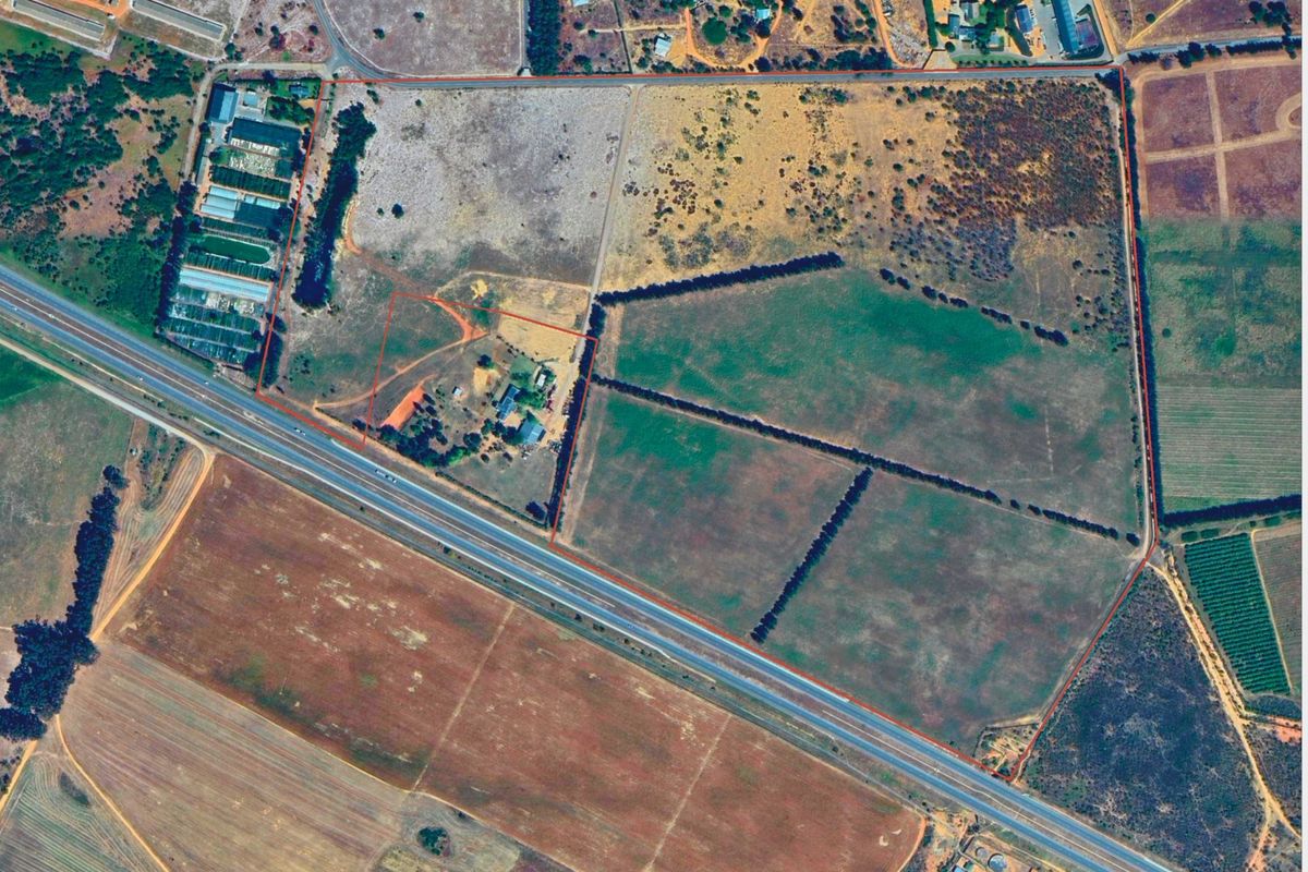 An aerial view of a large residential vacant land parcel with defined boundaries, showing open fields and access roads.