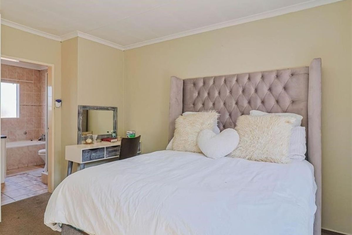 A bedroom featuring neutral wall tones and an en-suite bathroom with tiled flooring and a bathtub.