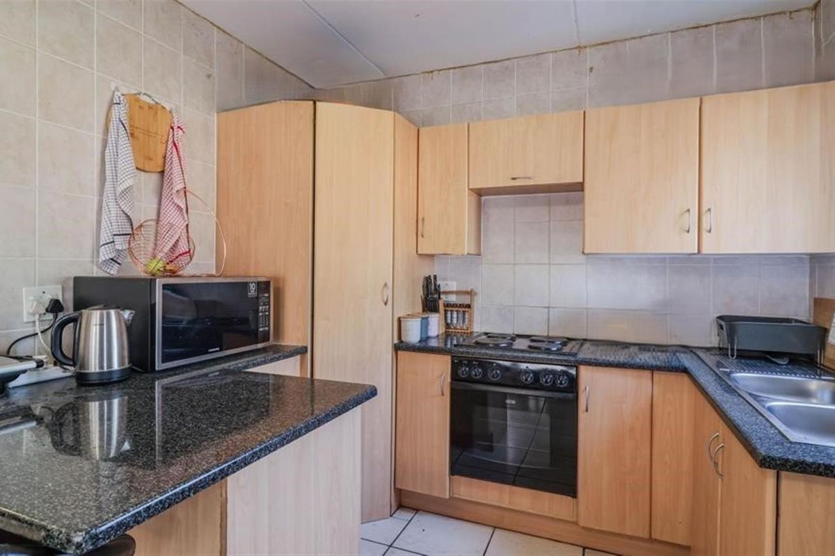 Functional kitchen featuring light wood-finish cabinetry, dark granite countertops, built-in oven, gas hob, and a double-basin stainless steel sink.