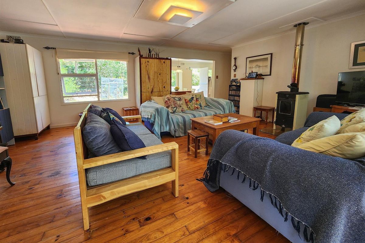Spacious living room featuring polished timber flooring, a built-in wood-burning fireplace, and large windows providing natural light and garden views.