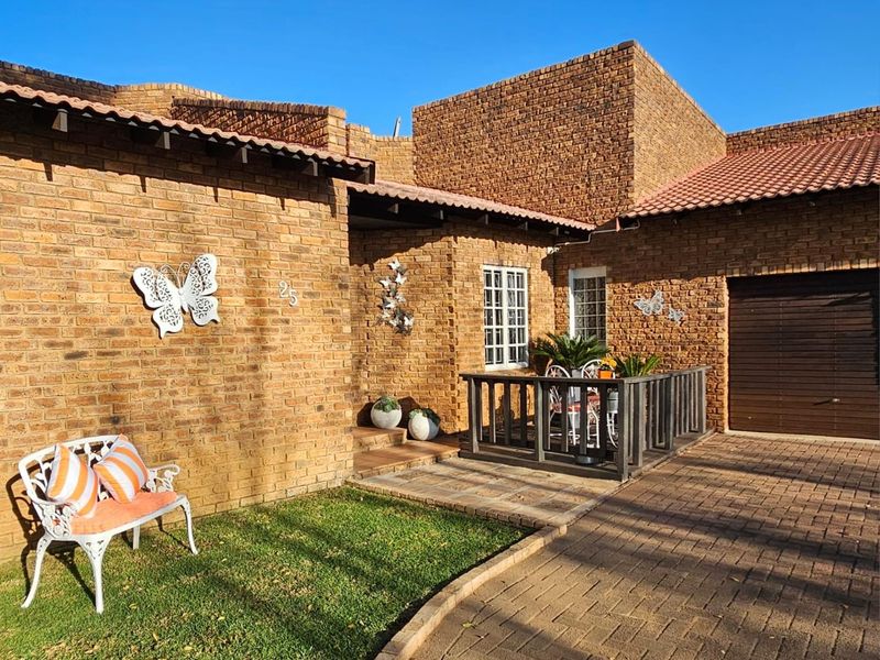 Front exterior view of a face-brick house featuring a paved driveway, small garden area, and a covered entrance porch with a wooden railing.