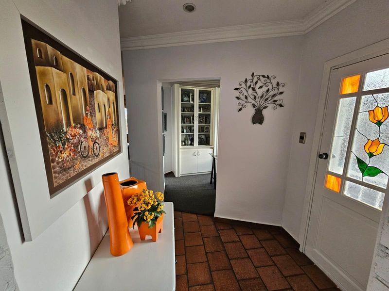 Entrance foyer featuring terracotta floor tiles, decorative stained glass front door, and built-in display cabinetry visible in the adjacent room.
