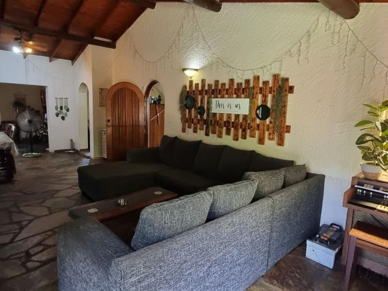 Spacious open-plan living and dining area featuring rustic flagstone flooring, exposed timber beam ceilings, and distinctive arched architectural details.