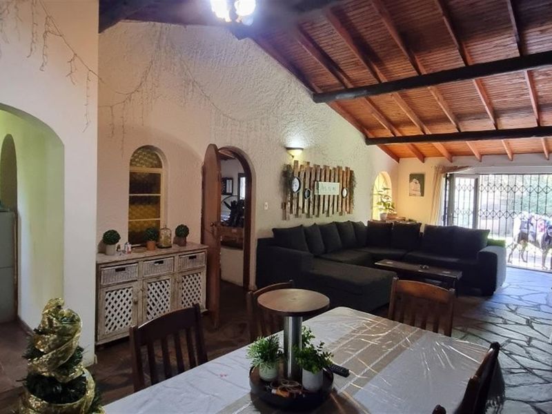 Spacious open-plan living and dining area featuring a vaulted timber ceiling, stone flooring, and charming arched architectural details leading to adjacent rooms.