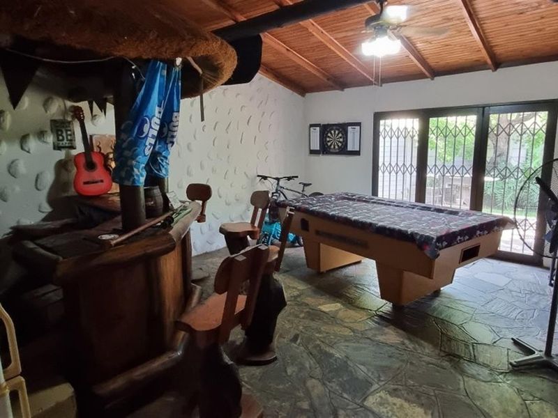 A rustic entertainment room featuring a built-in bar, exposed timber ceiling, and stone flooring, providing a dedicated space for leisure and social gatherings.