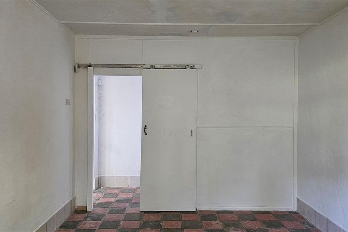 An empty interior room featuring a sliding door, tiled flooring, and visible signs of wear on the ceiling and wall surfaces.