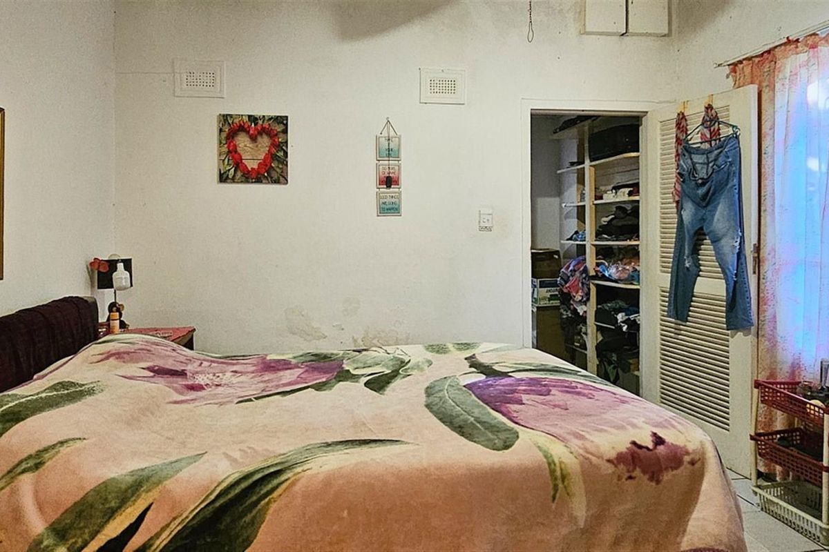 A bedroom featuring built-in shelving in the closet area and standard wall ventilation vents.