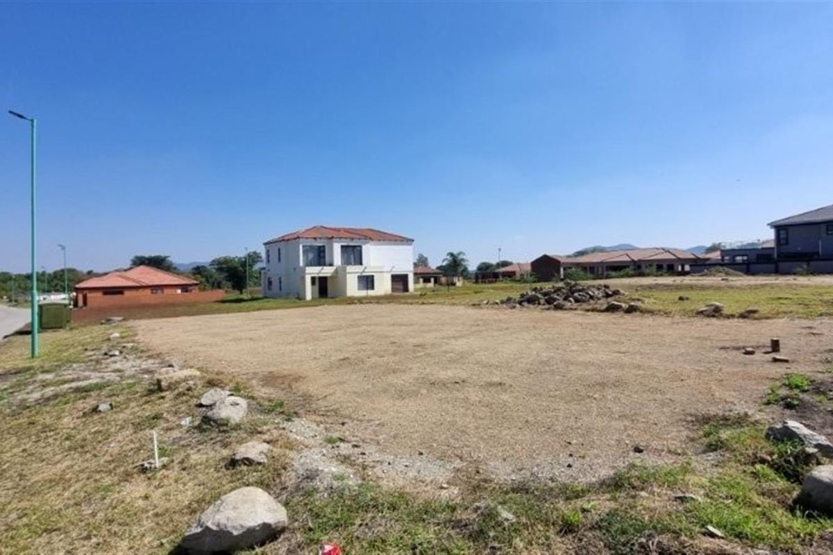 A vacant residential plot situated in a developed estate, featuring street access and utility connection points, ready for new construction.