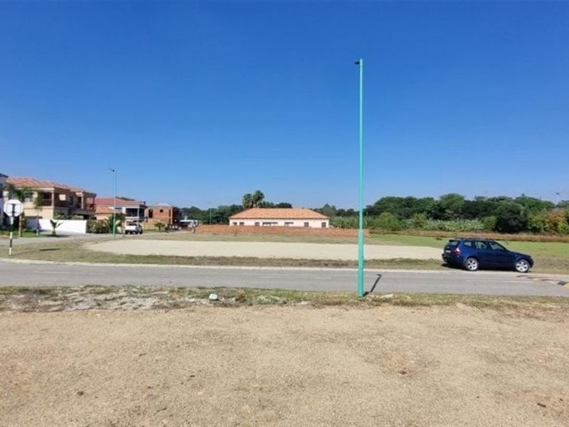 A view of a vacant residential plot situated in a developed neighborhood with access to paved roads and street infrastructure.