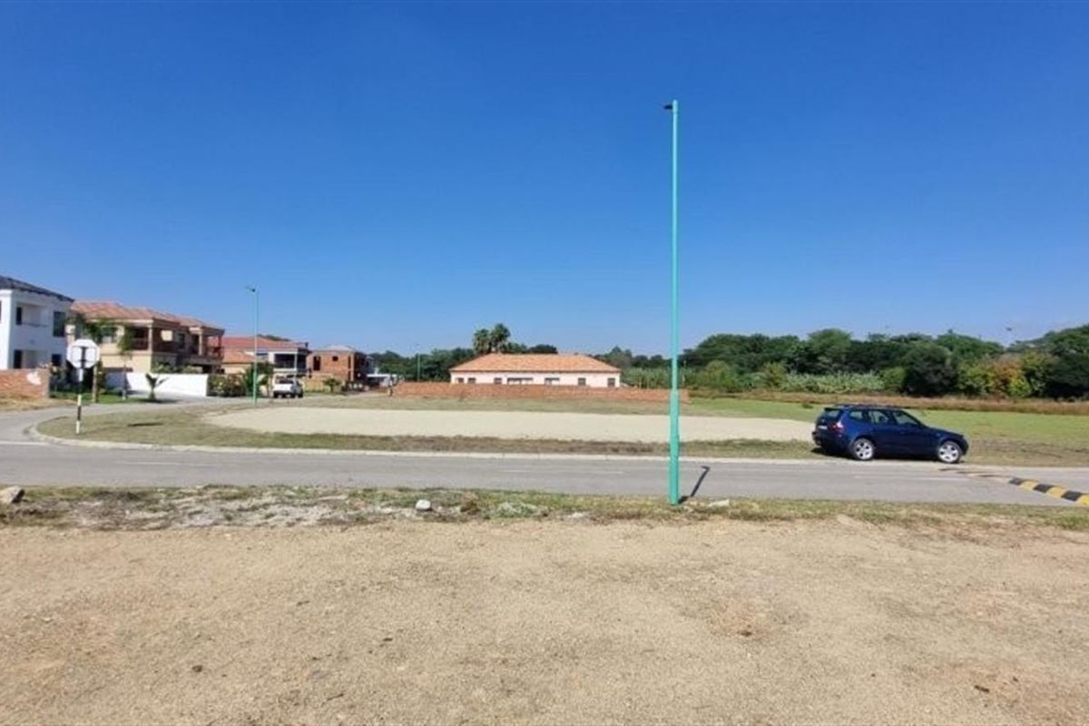 A view of a vacant residential plot situated in a developed neighborhood with access to paved roads and street infrastructure.