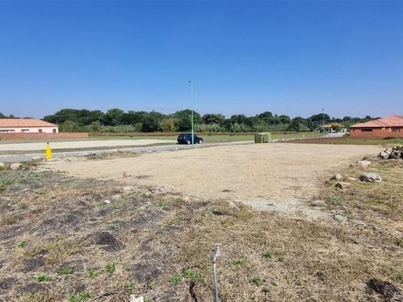 A vacant residential plot featuring a level building area, street access, and existing utility connections in a developed neighborhood.