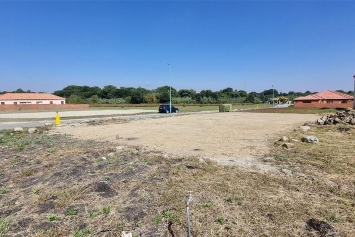 A vacant residential plot featuring a level building area, street access, and existing utility connections in a developed neighborhood.