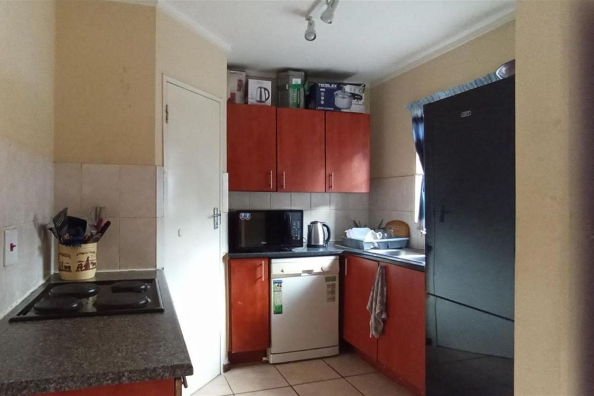 Functional kitchen featuring wood-tone cabinetry, tiled splashbacks, built-in hob, and tiled flooring in a compact layout.