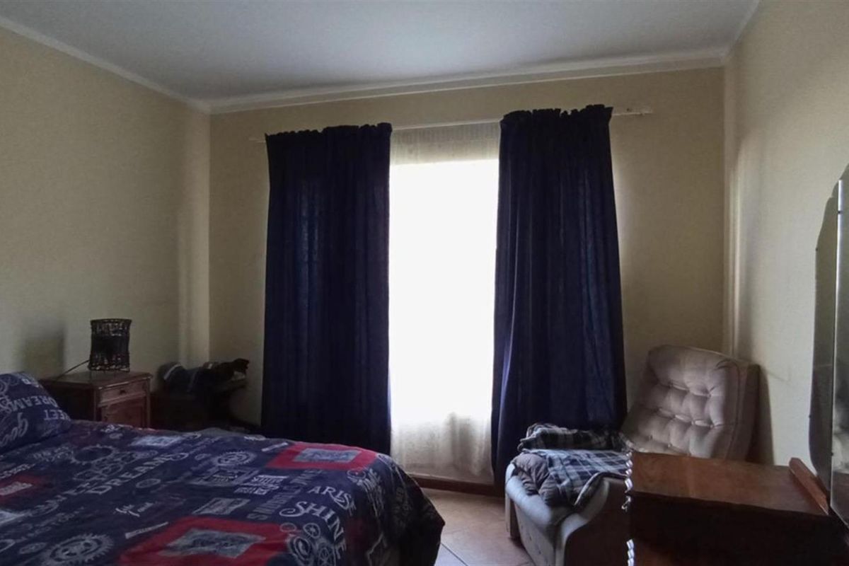 A bedroom featuring tiled flooring and a window with curtain fixtures.