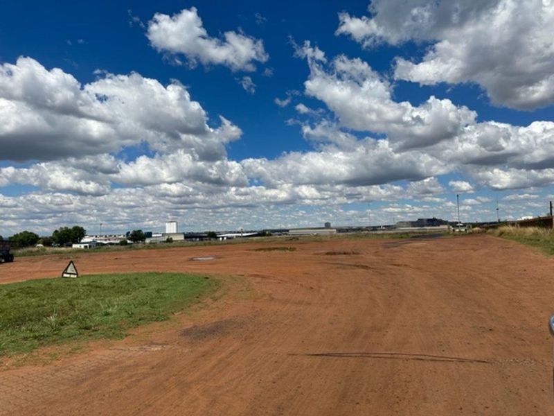 An expansive, undeveloped industrial plot featuring open, unpaved ground under a clear sky, suitable for various industrial development opportunities.