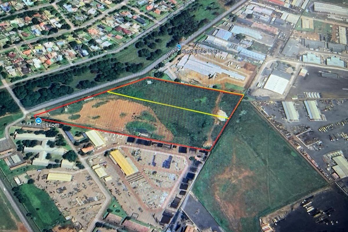 Aerial view of a large, undeveloped industrial land parcel with clear boundary markings, situated in an established industrial zone.