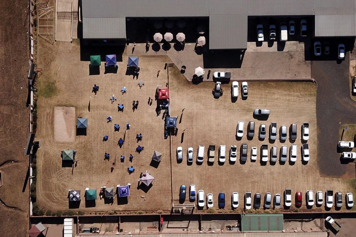 Aerial view of an industrial property featuring a large parking lot, open yard space, and building structure with metal roofing.