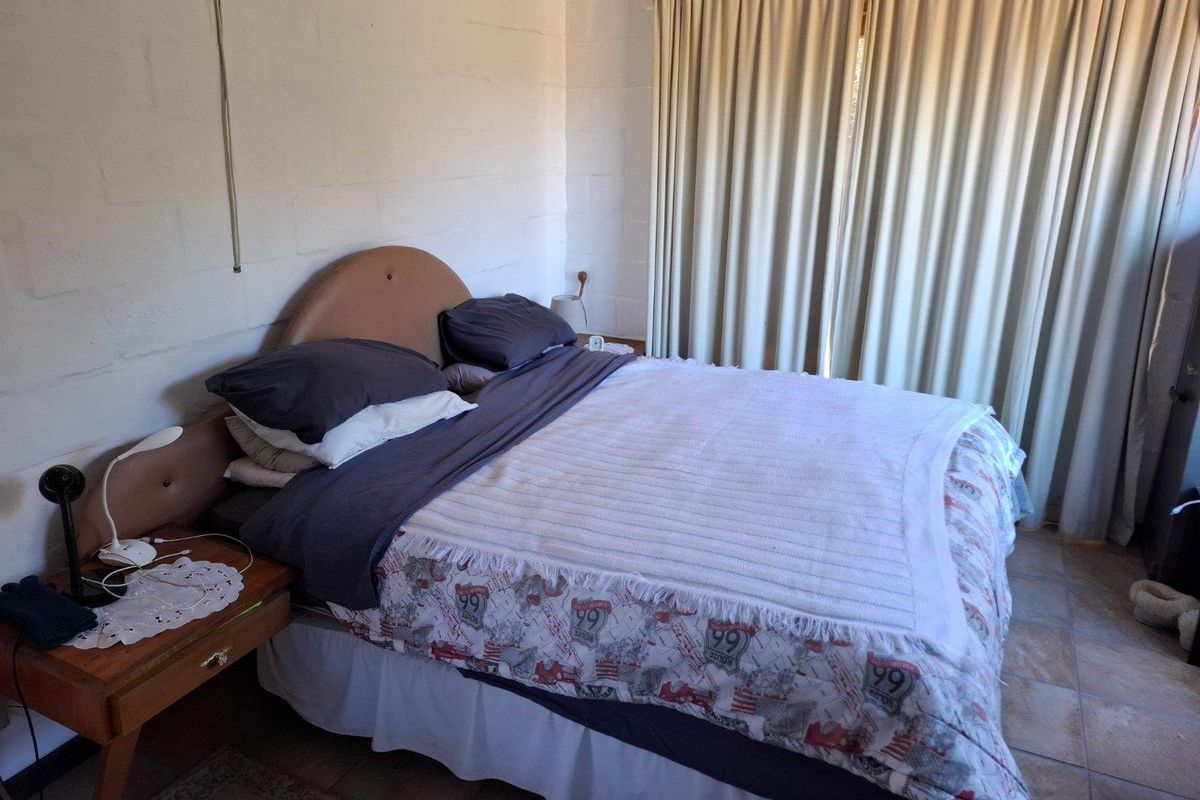 A bedroom featuring painted blockwork walls, tiled flooring, and floor-to-ceiling curtains.