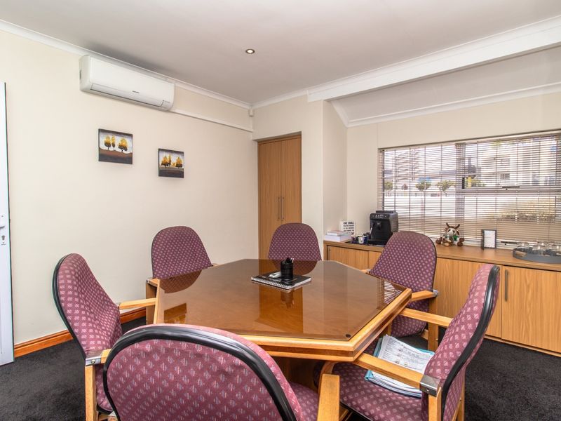 A functional office space featuring built-in cabinetry, a split-system air conditioner, and venetian blinds, providing a professional environment for meetings or daily work.