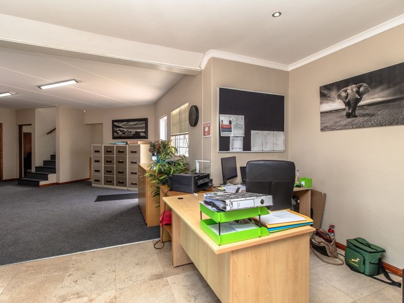 A functional office space featuring a mix of tiled and carpeted flooring, recessed lighting, and an integrated staircase leading to an upper level.