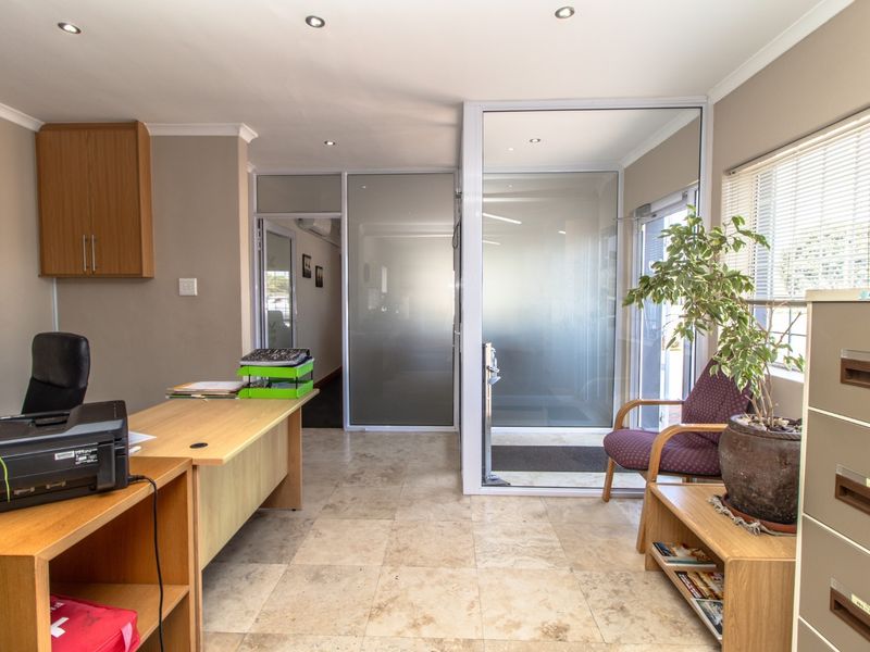 A professional office space featuring tiled flooring, recessed downlights, and modern frosted glass partitions, providing a bright and functional work environment.