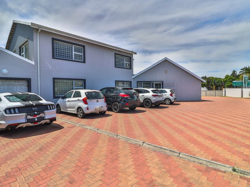 Front exterior view of the office building featuring a paved parking area, security-fitted windows, and a garage entrance.