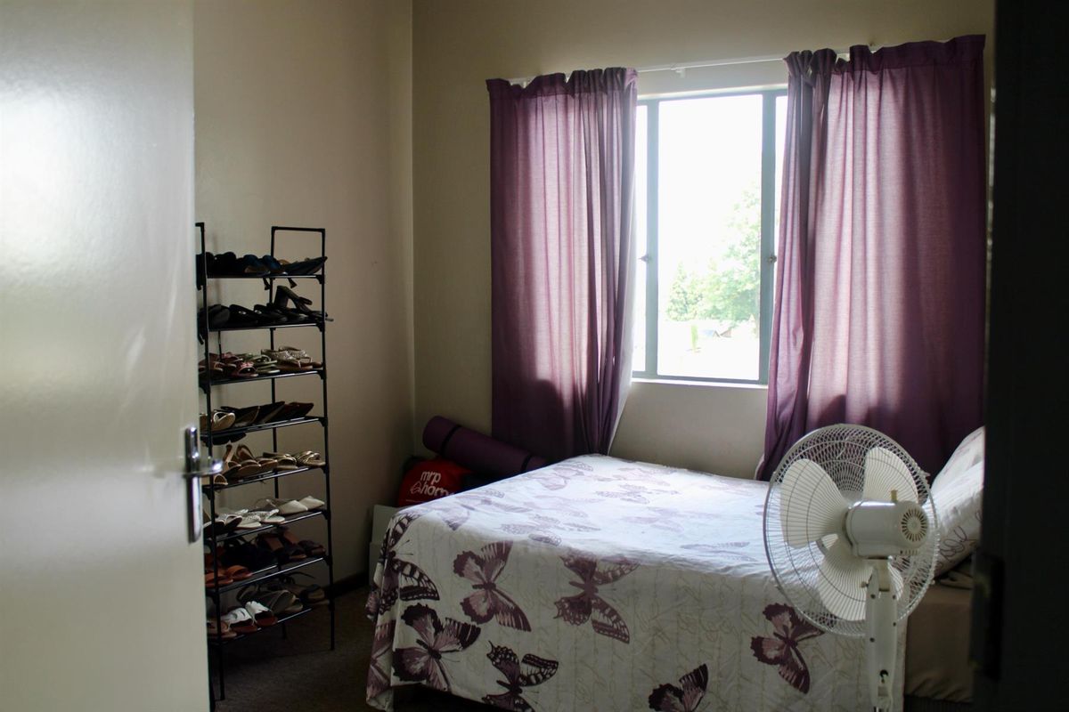 A standard bedroom featuring a window with curtains and carpeted flooring, providing a functional living space.