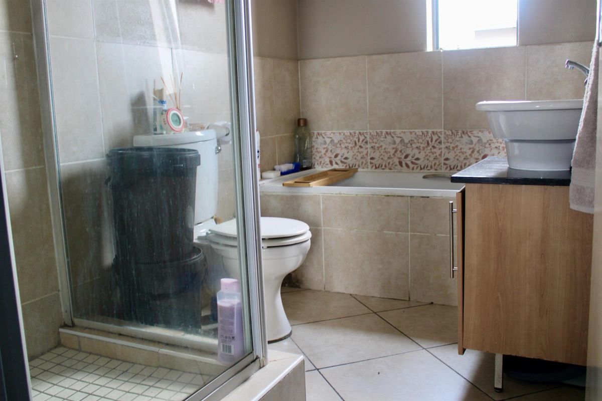A functional bathroom featuring a separate shower enclosure, a built-in bathtub with tiled surround, and a vanity unit with a basin.