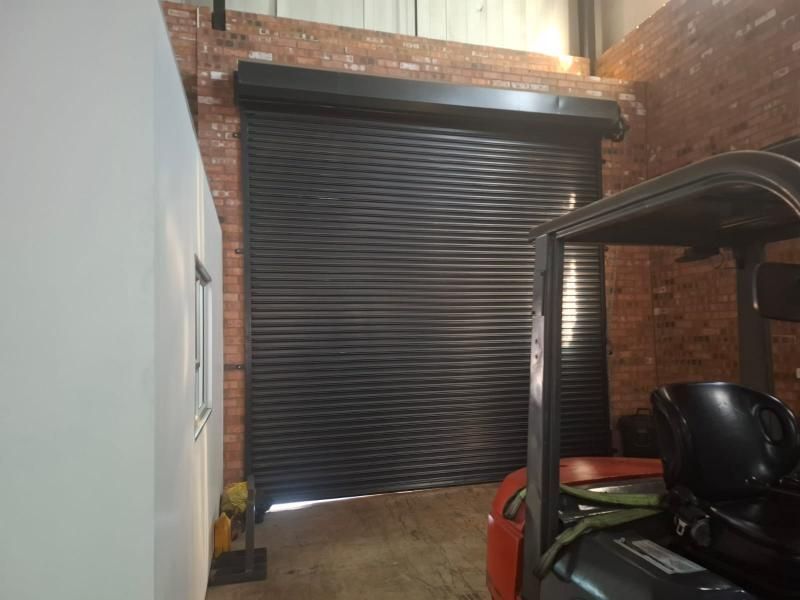 Commercial warehouse space featuring exposed brick walls and a large industrial roller shutter door, providing secure access for loading and operations.