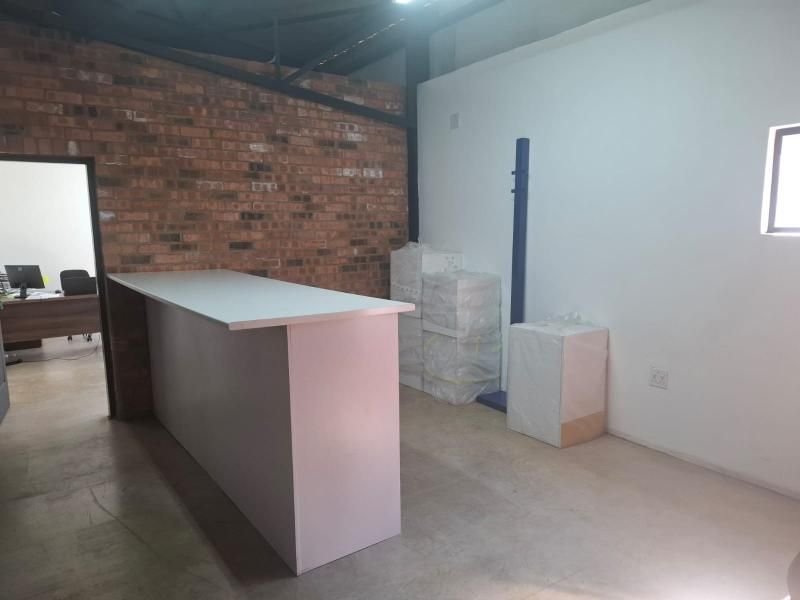 A commercial office space featuring an exposed brick wall, concrete flooring, and a built-in reception counter, offering a modern industrial aesthetic.
