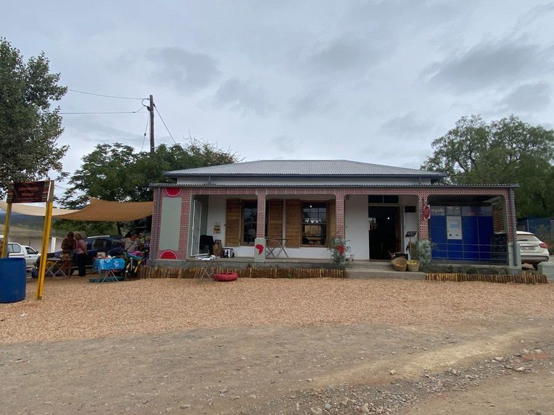 Front elevation of a commercial building featuring a covered veranda, decorative tiled columns, timber shutters, and an integrated parcel locker facility.