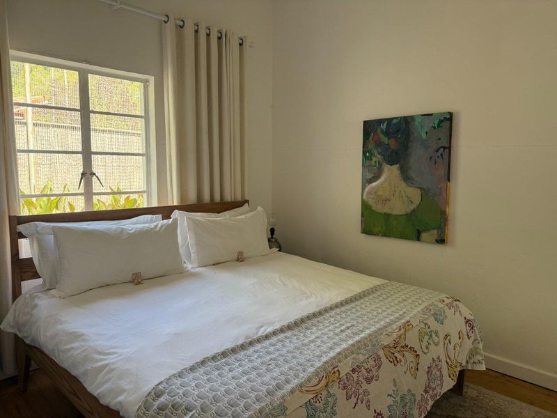 A well-maintained bedroom featuring a steel-framed window with natural light and neutral wall finishes.