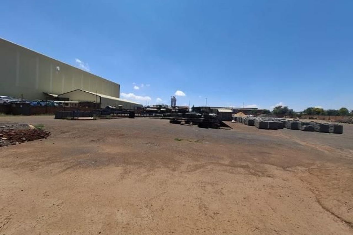 Expansive industrial yard area featuring a large warehouse structure and open storage space for materials.