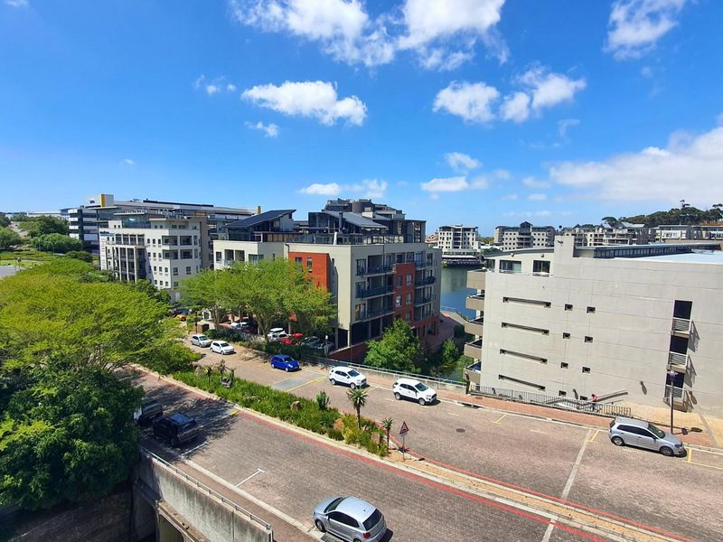 Elevated view overlooking the surrounding apartment complex, street infrastructure, and nearby water feature.