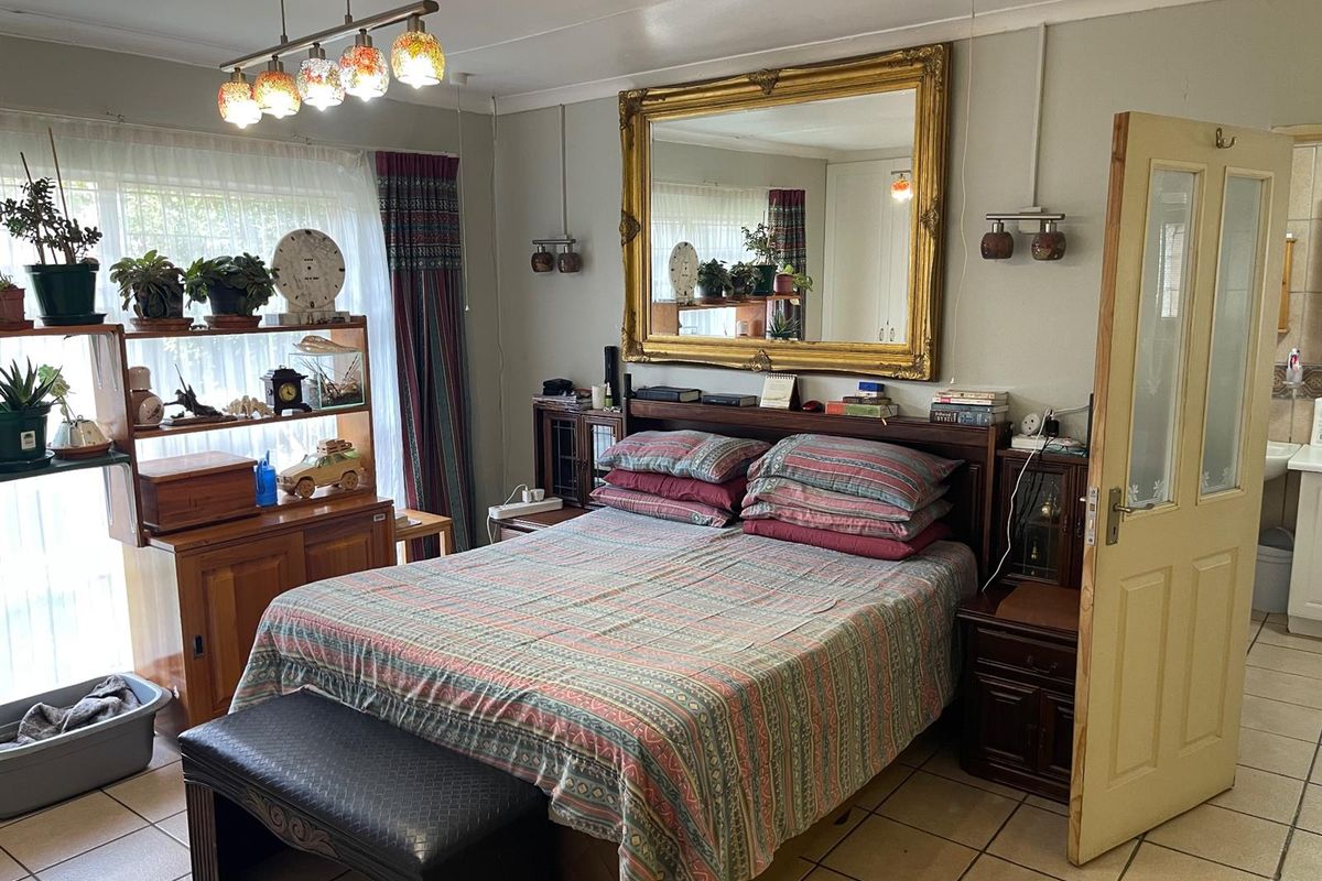 A bedroom featuring tiled flooring, built-in headboard cabinetry, and a large wall-mounted mirror, providing a functional and well-lit sleeping space.