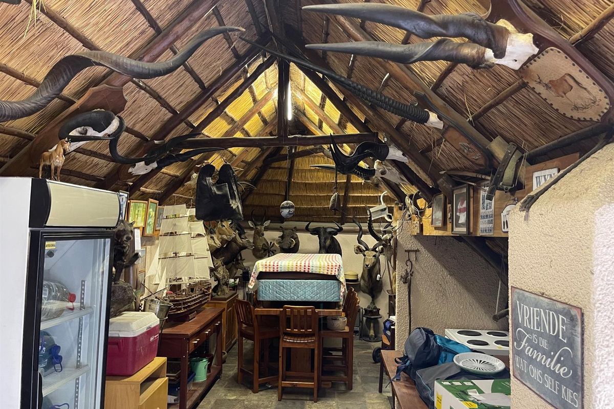 A rustic entertainment area featuring a high-pitched thatched roof, exposed timber beams, and stone-tiled flooring, creating a traditional lodge-style atmosphere.