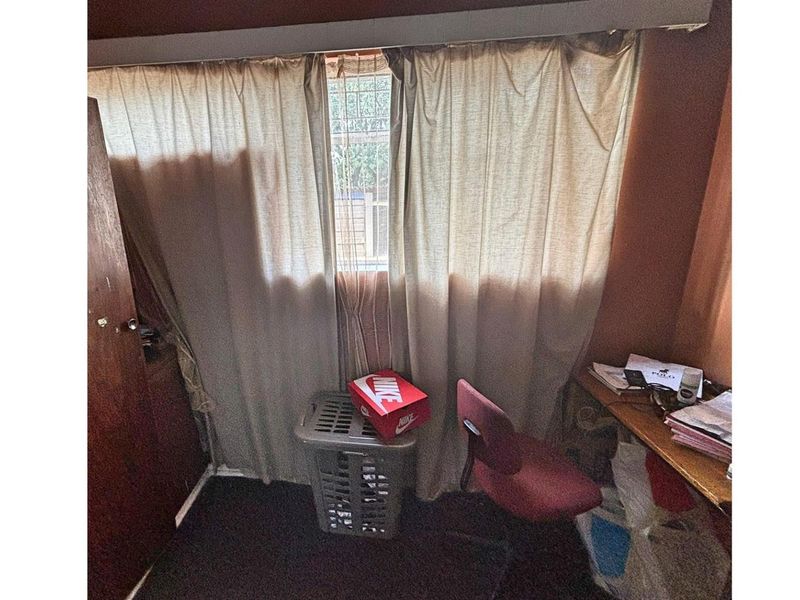 A bedroom featuring dark carpeting and a window with curtains, providing a functional space for rest or study.