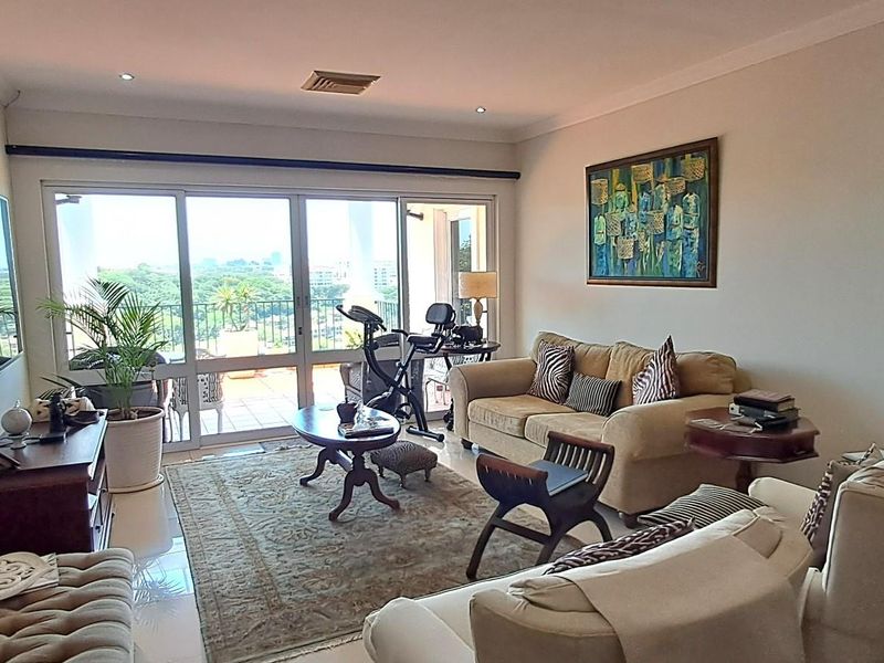 A bright and spacious living room featuring large sliding glass doors that open onto a balcony, providing natural light and scenic views.