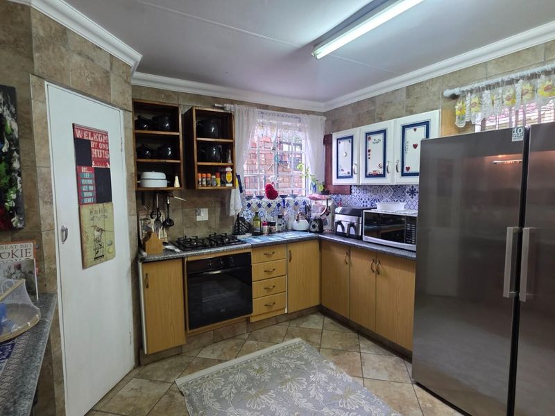 A functional kitchen featuring wooden cabinetry, a gas hob, built-in oven, and tiled finishes throughout.
