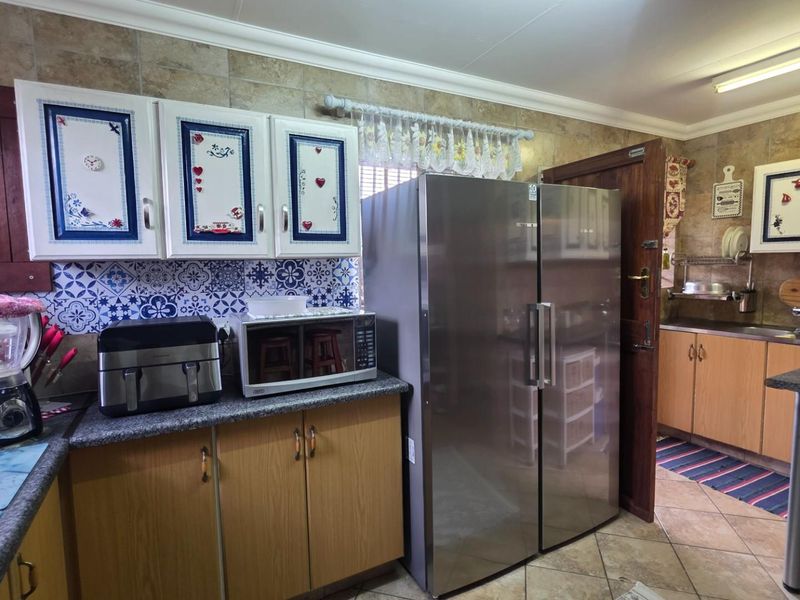 A functional kitchen featuring wood-finish cabinetry, tiled backsplash, laminate countertops, and a double sink, offering a practical layout for daily meal preparation.