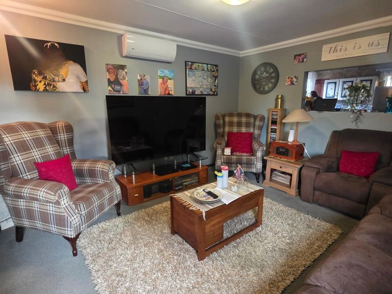 A comfortable living room featuring a wall-mounted split-system air conditioner and a convenient pass-through window connecting to the adjacent kitchen area.