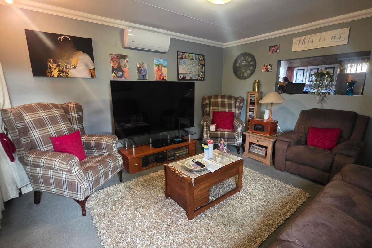 A comfortable living room featuring a wall-mounted split-system air conditioner and a convenient pass-through window connecting to the adjacent kitchen area.