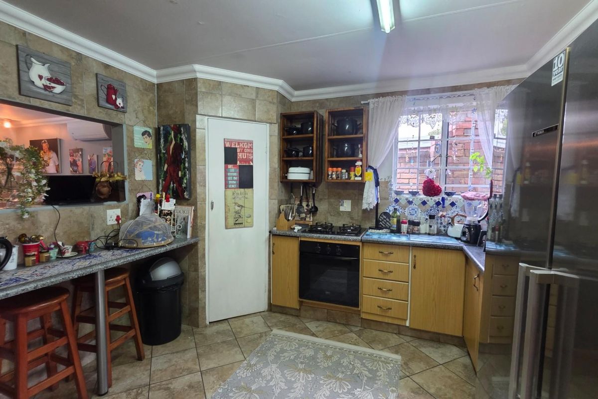 A functional kitchen featuring laminate cabinetry, a built-in oven with gas hob, tiled splashbacks, and a convenient breakfast bar area.